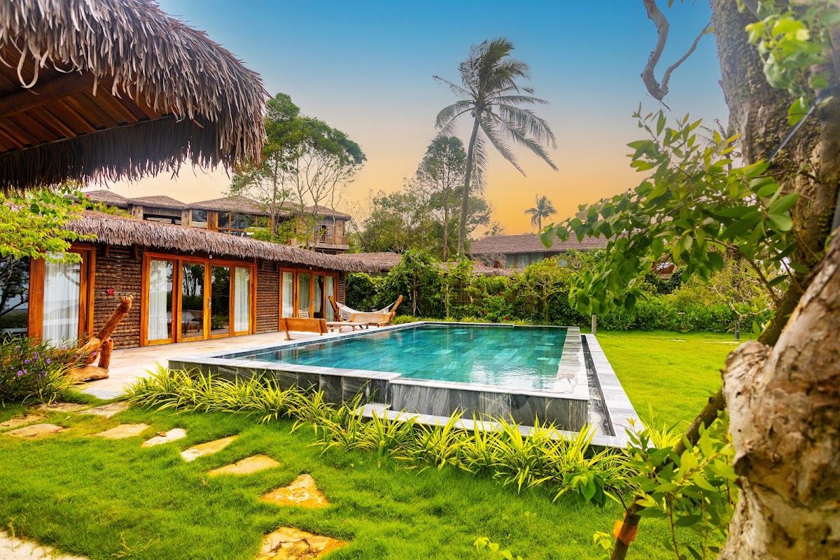 A private pool villa with tropical garden and thatched roof at a Phu Quoc resort in golden evening light